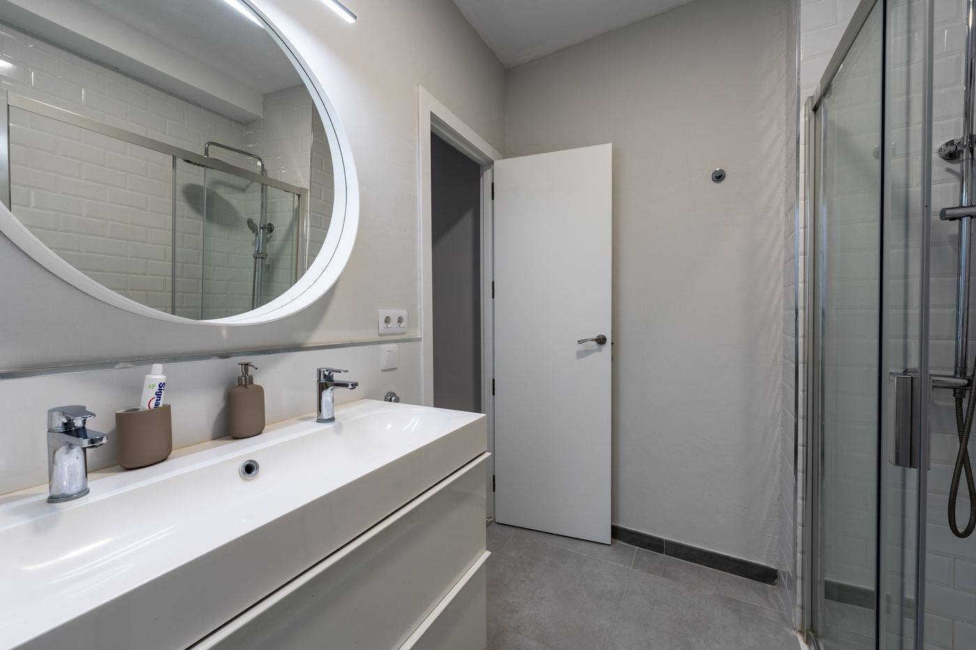 Bathroom with double sink and round mirror